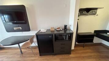 Een kleine kamer met een bureau, stoel en een wandgemonteerde flatscreen-tv.