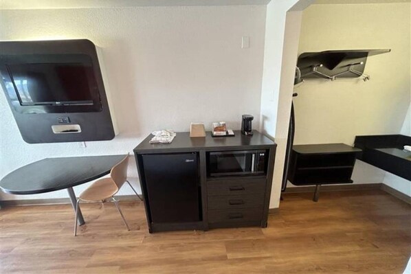 Een kleine kamer met een bureau, stoel en een wandgemonteerde flatscreen-tv.