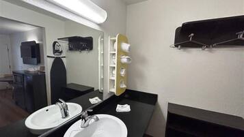 Een hotelbadkamer met twee wasbakken, een spiegel, een handdoekrek en een plank met toiletartikelen.