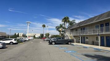 A parking lot with a building on the right, including a ramp and a blue handicapped parking space.