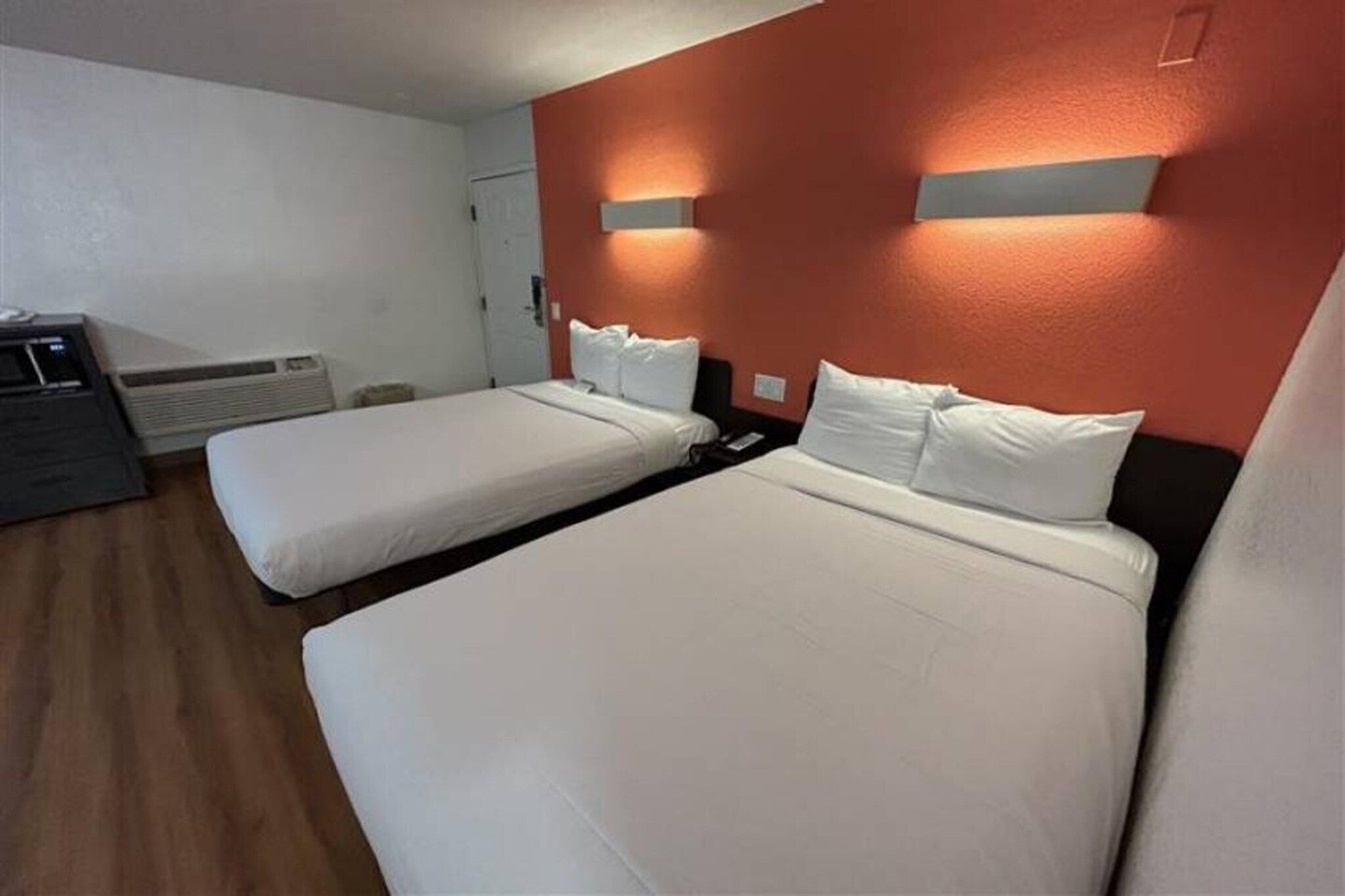 Hotellihuone, jossa on kaksi sänkyä, työpöytä ja lämmitin.