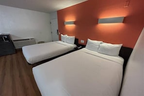 Hotellihuone, jossa on kaksi sänkyä, työpöytä ja lämmitin.