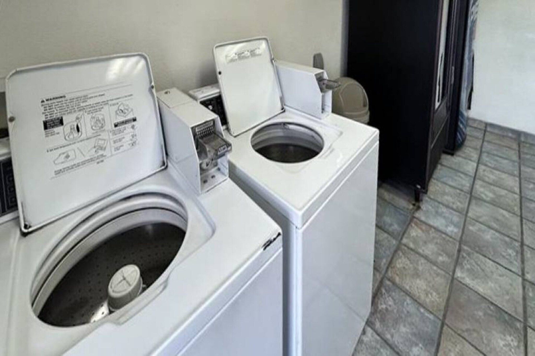A laundry room with two front-loading washing machines and a dryer.
