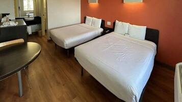 A hotel room with two beds, a desk, and a bathroom.