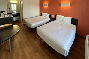 Habitació d'hotel amb dos llits, una taula de treball i un bany.
