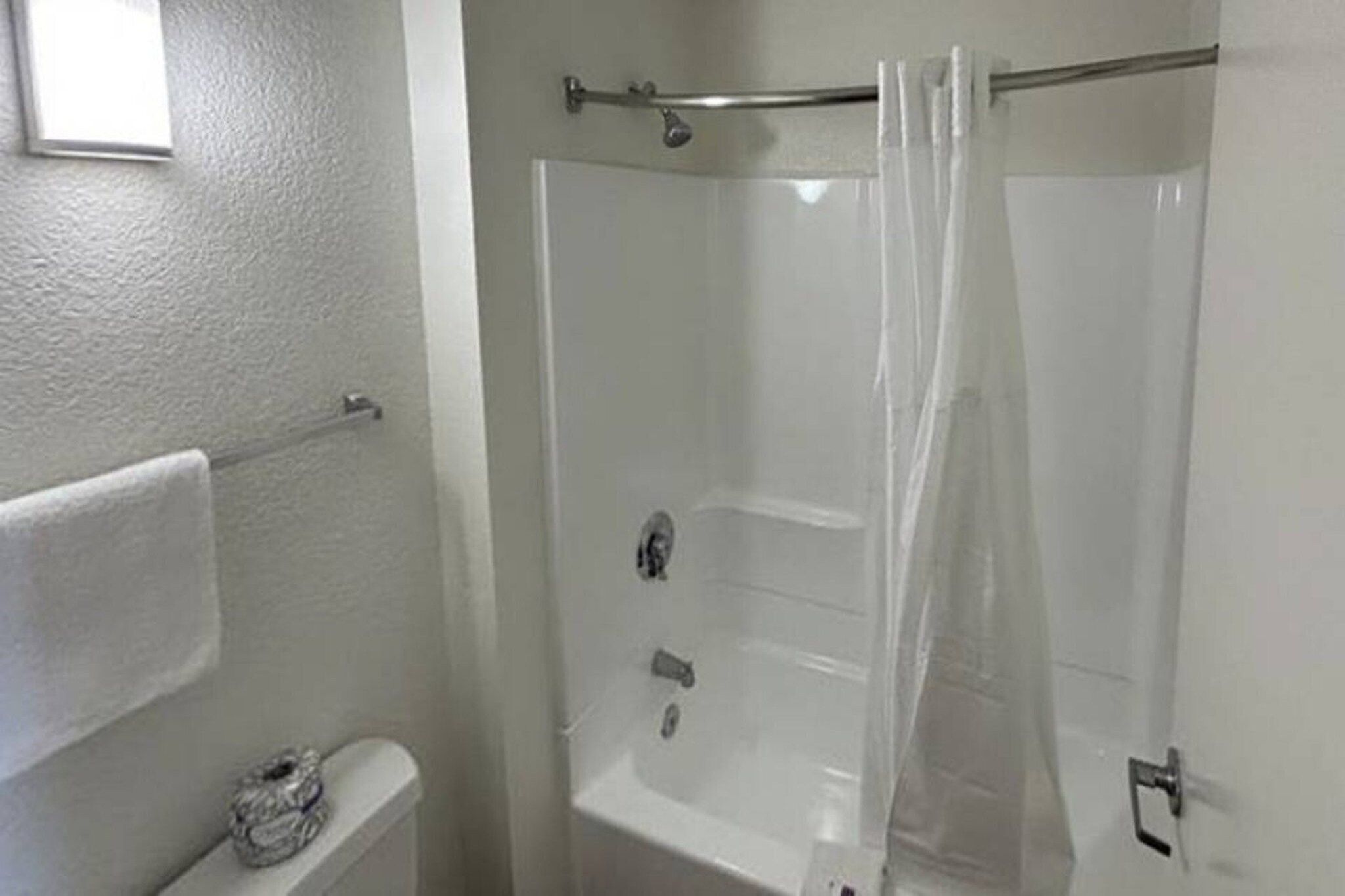 A bathroom with a shower, toilet, and towel rack.