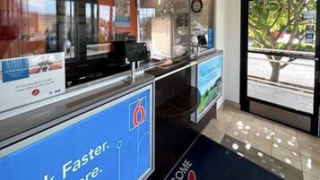 A reception area with a blue sign reading 'Faster. More.' and a welcome mat.