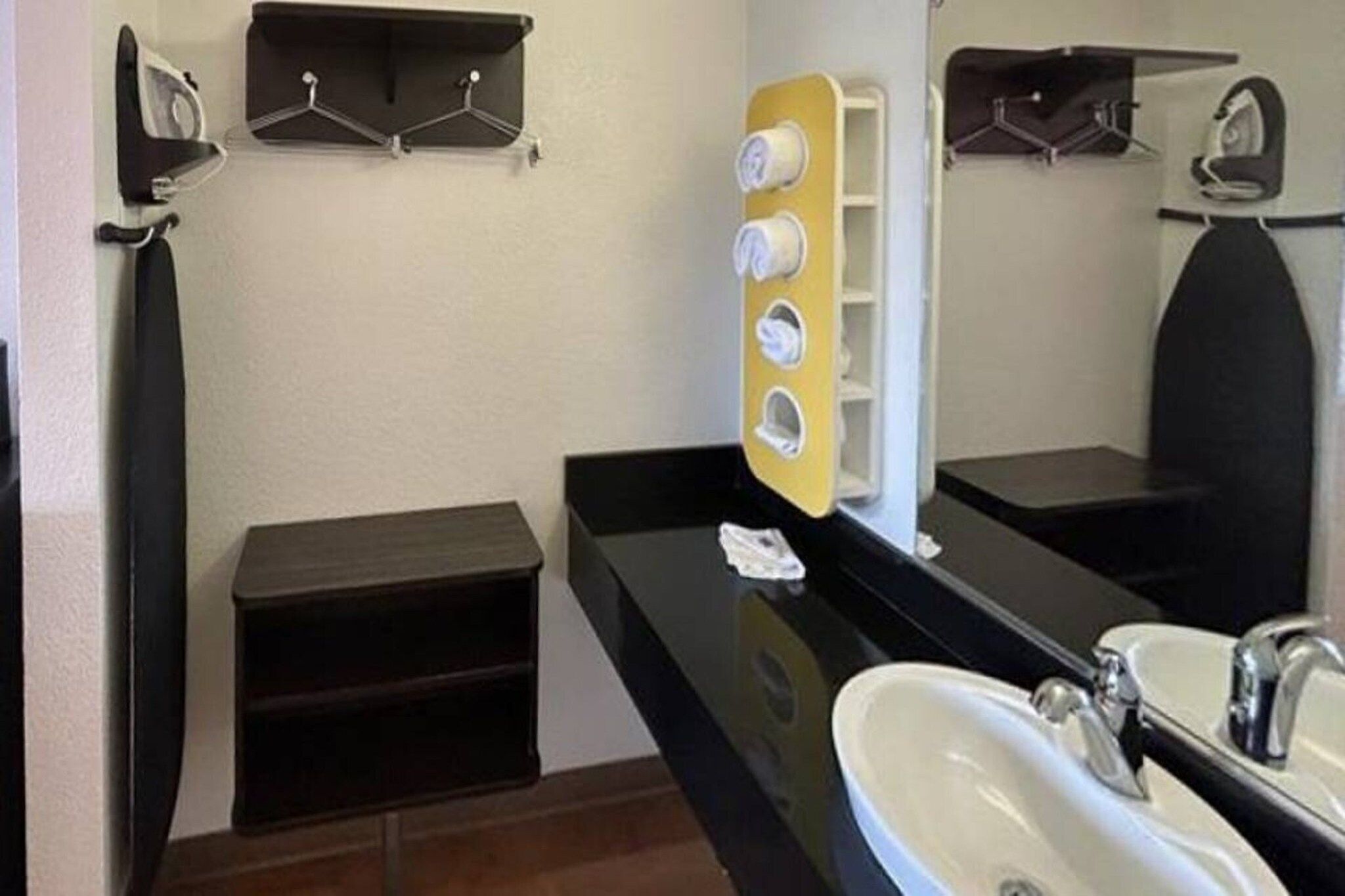 Un baño con lavamanos, espejo y toallero.