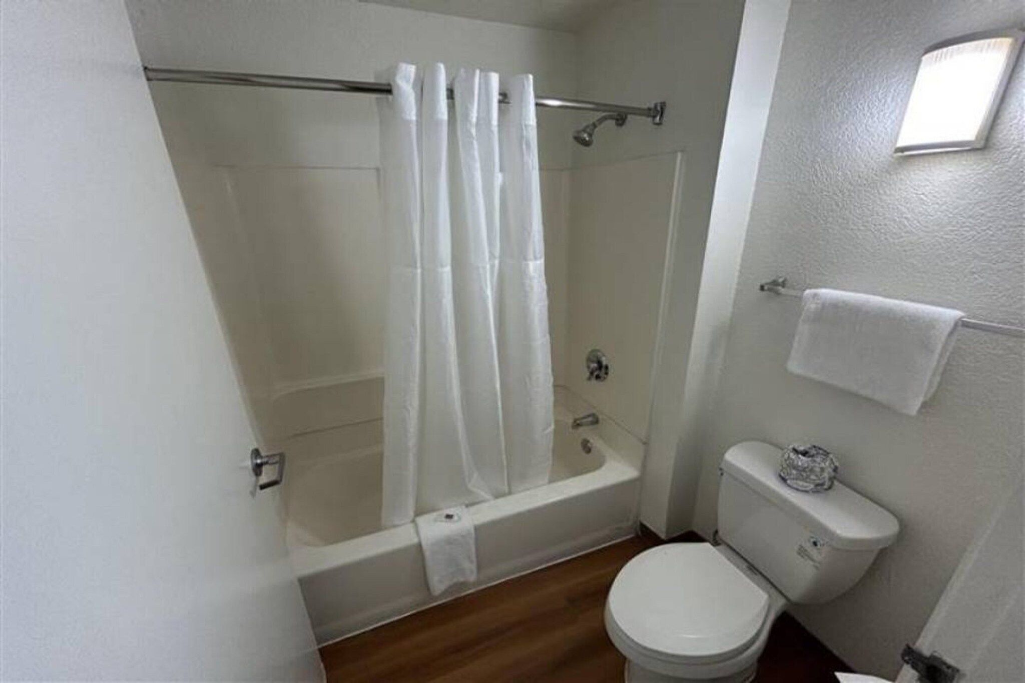 A bathroom with a shower, toilet, and a towel rack.
