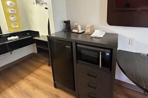 Una cuineta compacta amb microones, nevera petita i cafetera al taulell.