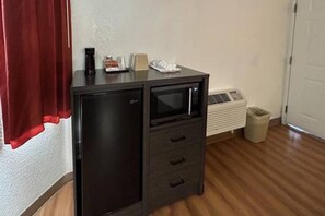 Een kleine keuken met een magnetron, een koelkastje en een afvalbak.