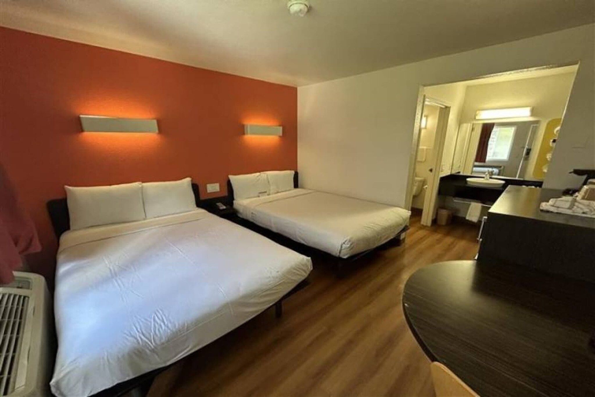 Een hotelkamer met twee bedden, een bureau en een badkamer die door een open deur zichtbaar is.