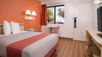 Een hotelkamer met een bed, bureau, stoel, raam en deur.