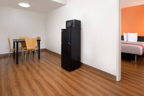 Ein Hotelzimmer mit Essbereich, einem schwarzen Kühlschrank und einem Bett an einer orangefarbenen Wand.