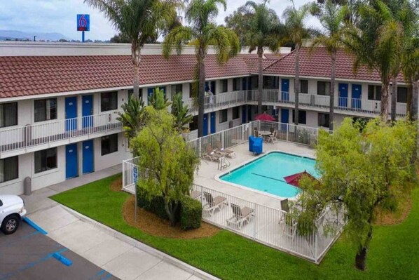 Ein Motel mit Schwimmbad, mehreren Balkonen und einem Parkplatz.