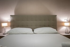 A neatly made bed with a tufted headboard, two bedside lamps, and a clean, uncluttered room layout. - Agnolo 48 (Florence)