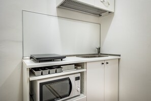 Eine kleine Küchenzeile mit Mikrowelle, kleinem Backofen, Spüle und Stauschubladen.
