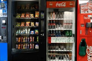 Een automaat met snacks en een Coca-Cola koelkast met diverse dranken.