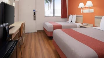 Habitación de hotel con escritorio, dos camas, televisor y ventana con vista a palmeras.