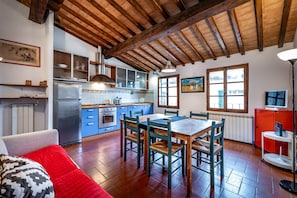 Una cocina amplia con vigas de madera, un comedor con sillas y un sofá rojo.