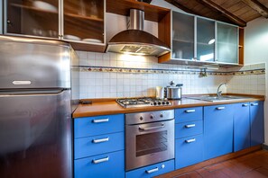 A kitchen with a stainless steel refrigerator, a gas stove, and blue cabinets. - Santa Maria (Florence)