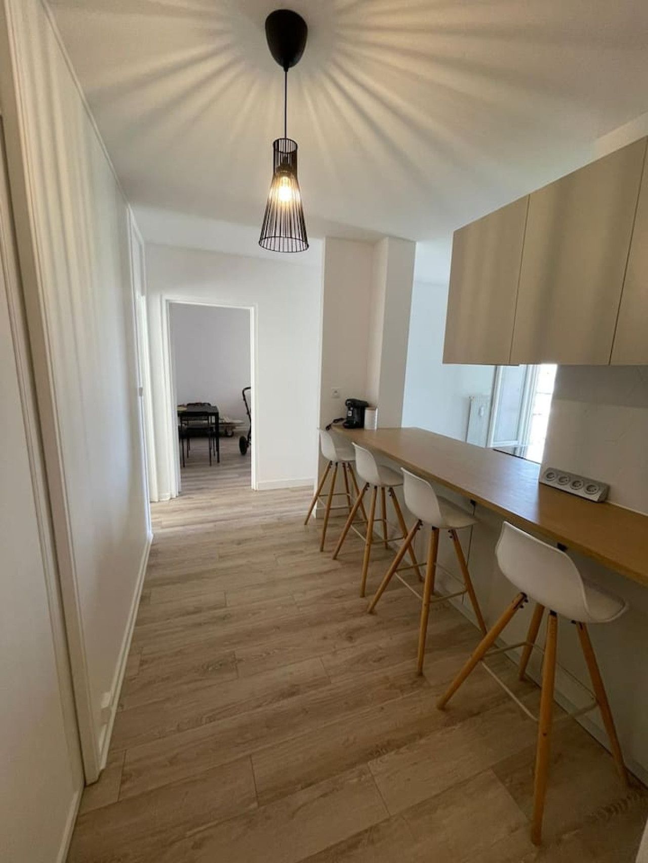 A modern kitchen with a wooden countertop, white chairs, and a pendant light.