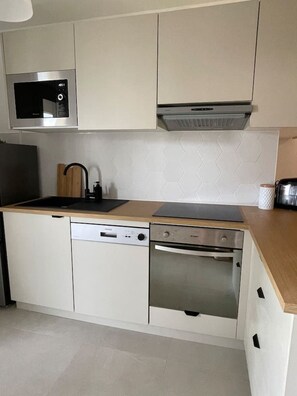 A modern kitchen with a microwave, dishwasher, and oven. - The Reims Getaway: City Center - Tram - Balcony & Wi-Fi (Reims)