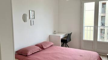 A bedroom with a bed, a desk, and a chair.