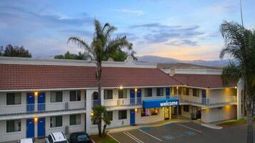 A motel with a 'welcome' sign, multiple floors, and a parking lot.