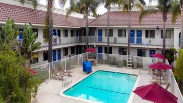 Um hotel com piscina, várias varandas e área de estar externa.