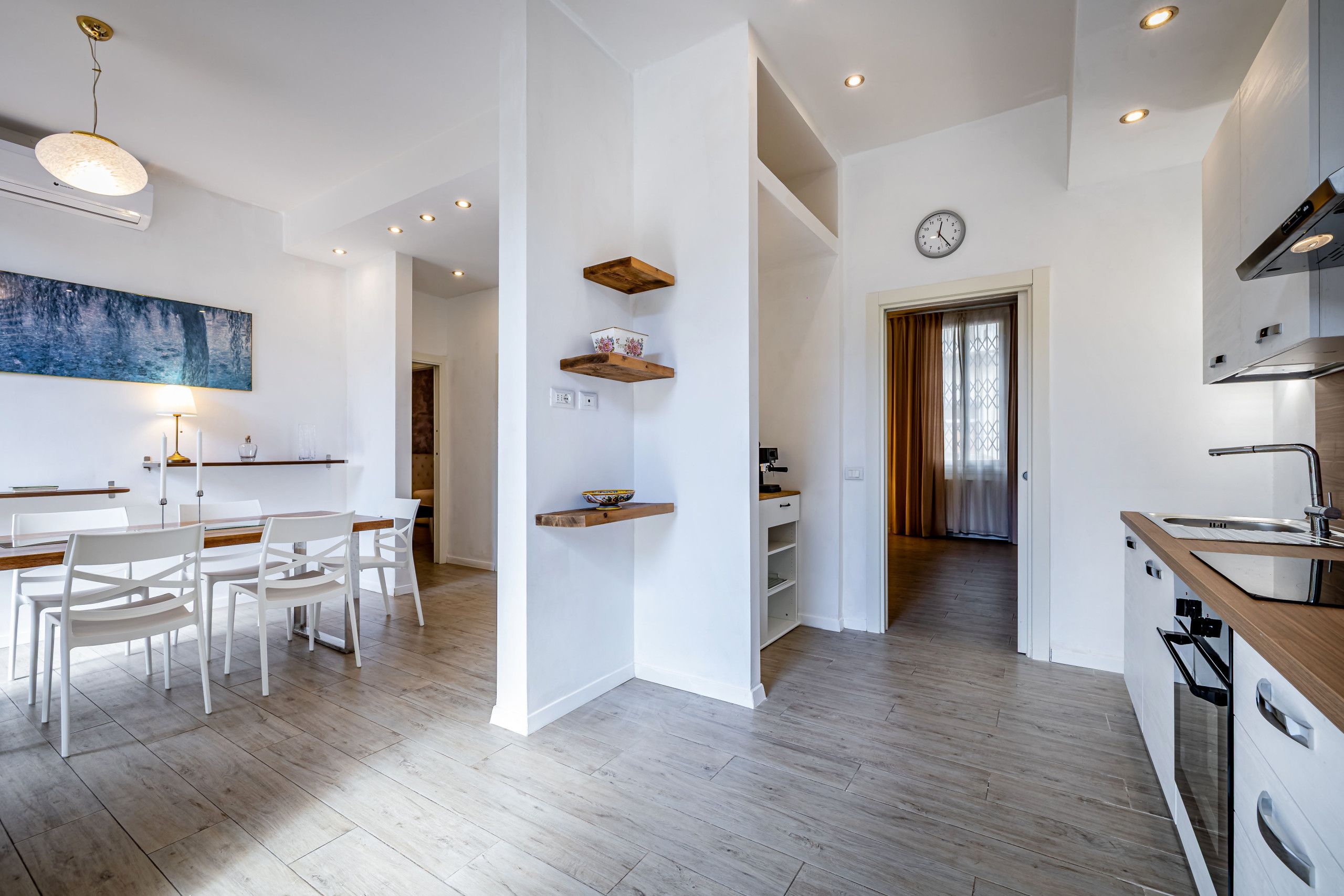 A modern kitchen with white cabinetry, a wooden countertop, and a built-in oven.