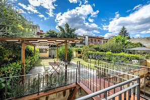Un patio con una pérgola, zona de estar y vistas de edificios circundantes.