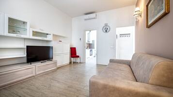 A modern living room with a flat-screen TV, a red chair, and a beige sofa.