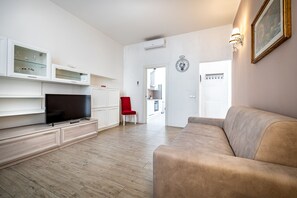 Een moderne woonkamer met een flatscreen televisie, een rode fauteuil en een beige bank.