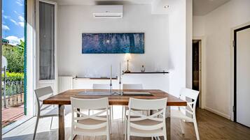 A modern dining area with a wooden table, white chairs, and a large abstract painting on the wall.