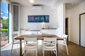 Een moderne eetruimte met een houten tafel, witte stoelen en een groot abstract schilderij aan de muur.