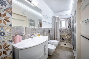 Un baño con lavamanos, inodoro y zona de ducha.