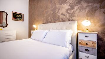 A bedroom with a bed, two bedside tables, a dresser, a mirror, and a framed picture on the wall.