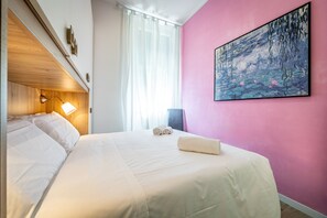 Habitación de hotel con cama, un cuadro en la pared y una ventana con cortinas.
