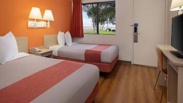 Quarto de hotel com duas camas, uma escrivaninha, televisão e janela com vista.