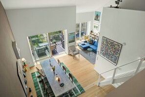 A spacious living area with a dining table, sofa, and a large window overlooking a balcony. - Østerbro flat with views over Copenhagen (København)