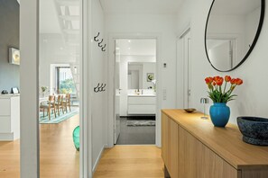 A modern kitchen with a wooden countertop, a blue vase with flowers, and a large mirror. - Østerbro flat with views over Copenhagen (København)