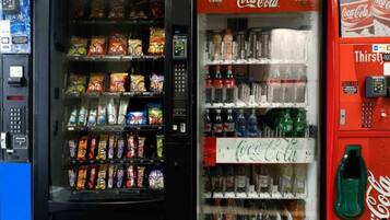Máquina de vendas com lanches e um refrigerador de Coca-Cola com diversas bebidas.