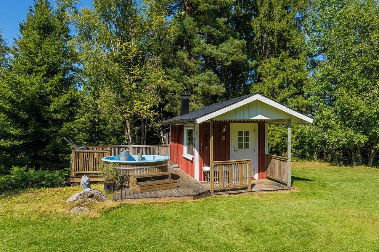 Eine Holzhütte mit Whirlpool, Terrasse und kleiner Veranda.