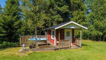 Eine Holzhütte mit Whirlpool, Terrasse und kleiner Veranda.