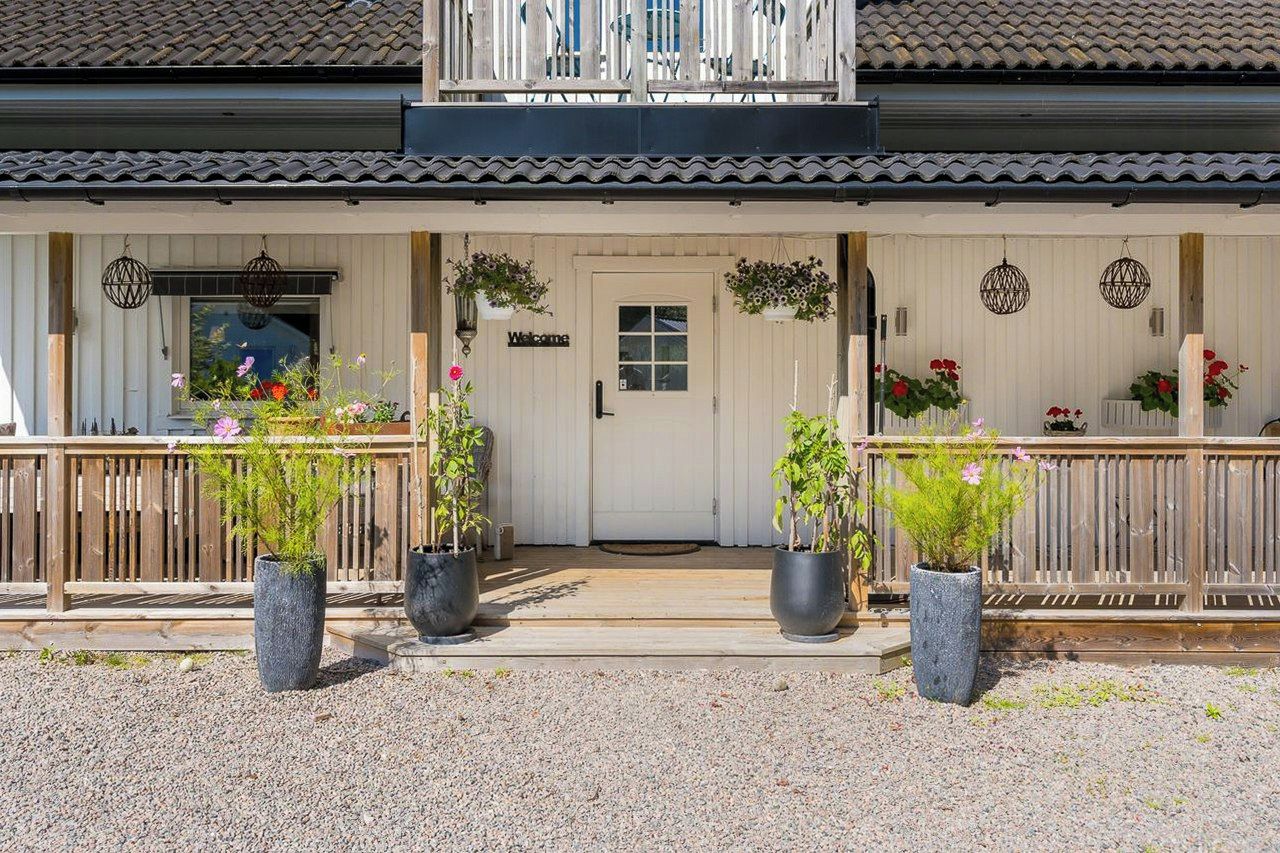 Een gebouw met een witte gevel, een houten balkon en potplanten ervoor.