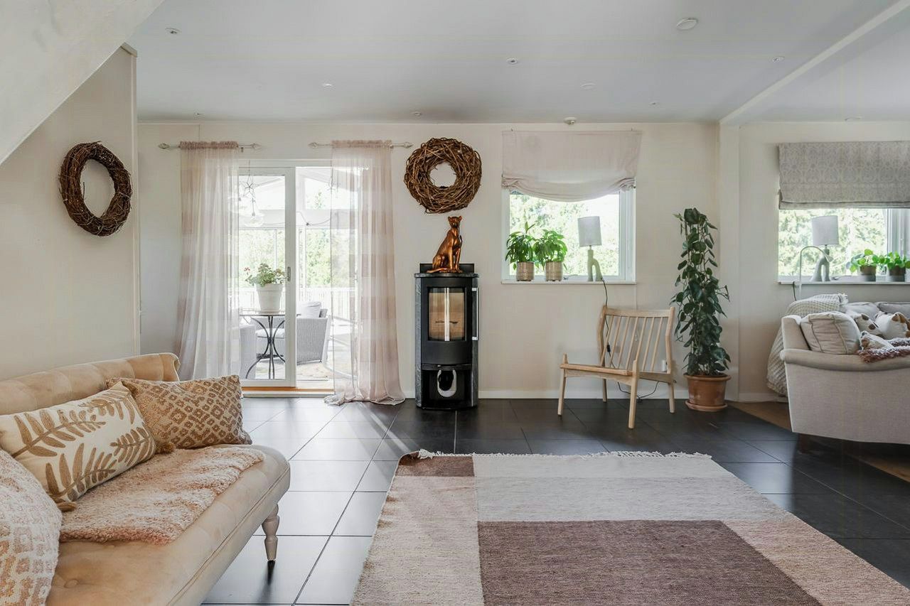 A living room with a sofa, a fireplace, a dining area, and a view of the outdoors.