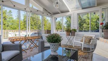 A sunlit room with a glass ceiling, wicker furniture, and potted plants.