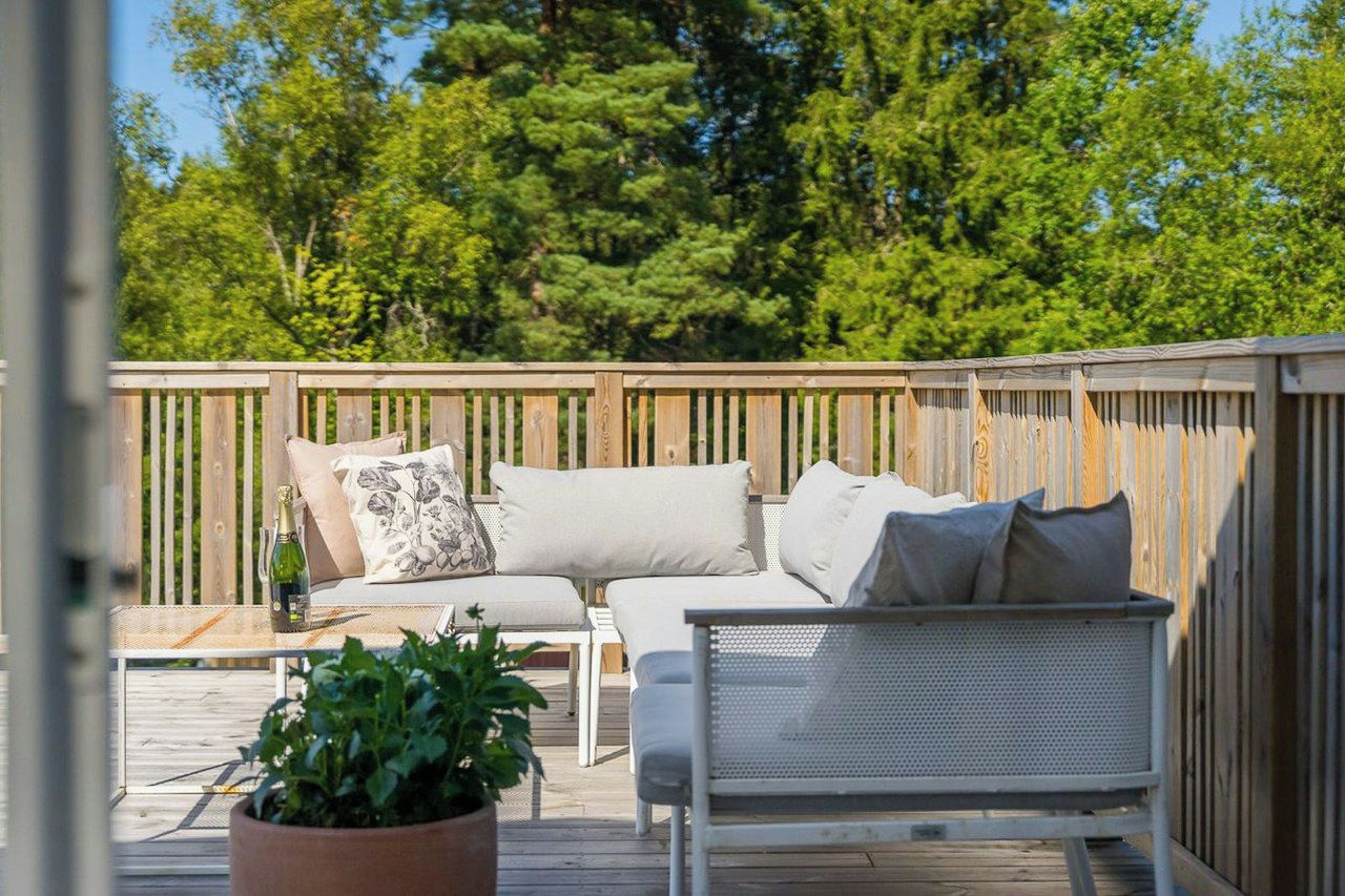 Eine Terrasse mit einer Couch, einem Sessel und einem Topf mit einer Pflanze.