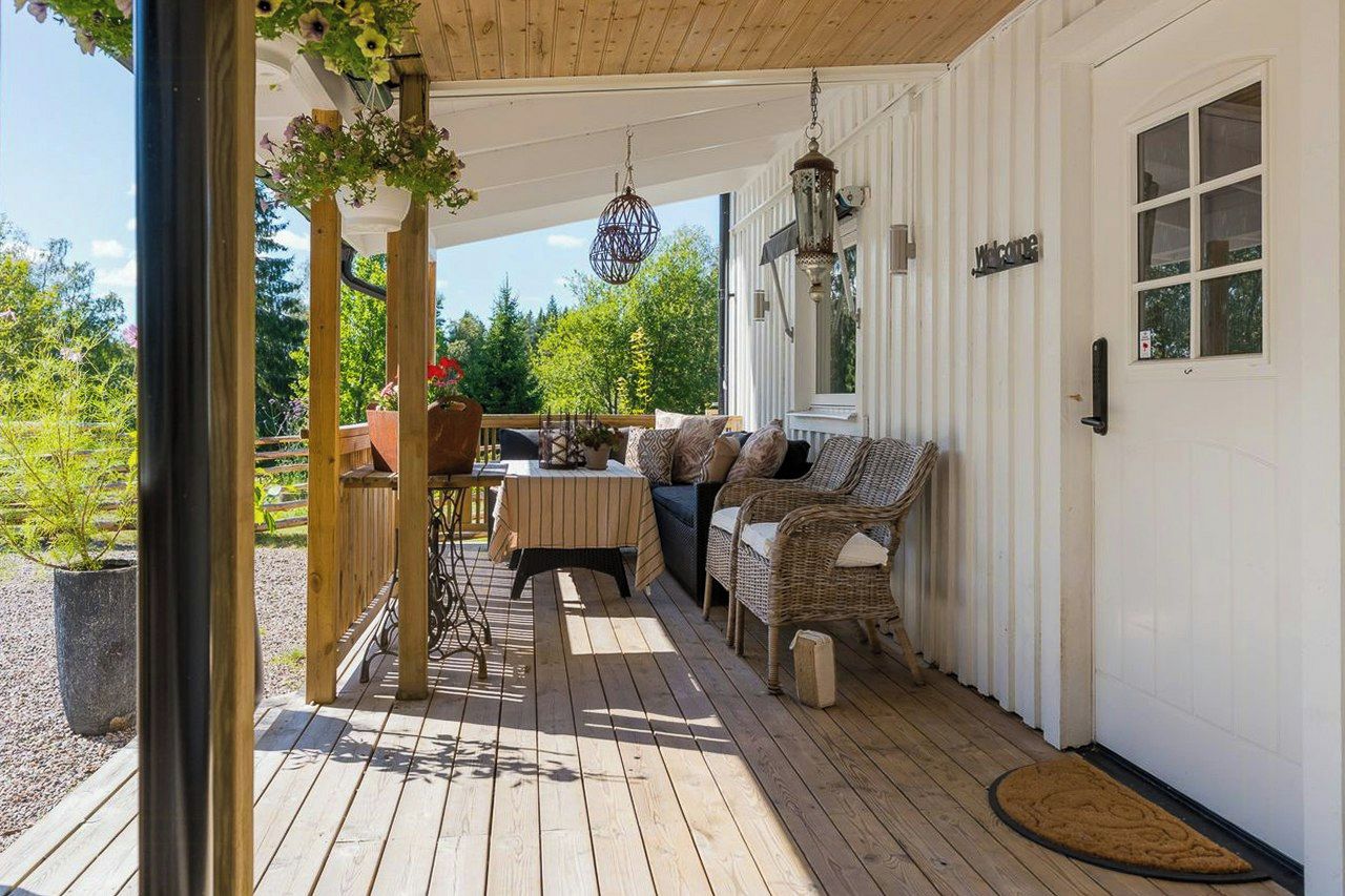 A covered porch with a seating area, a table, and hanging decorations.
